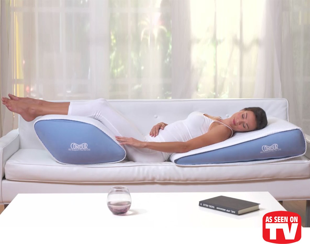 Woman lying on a sofa using contour leg pillow and contour head pillow