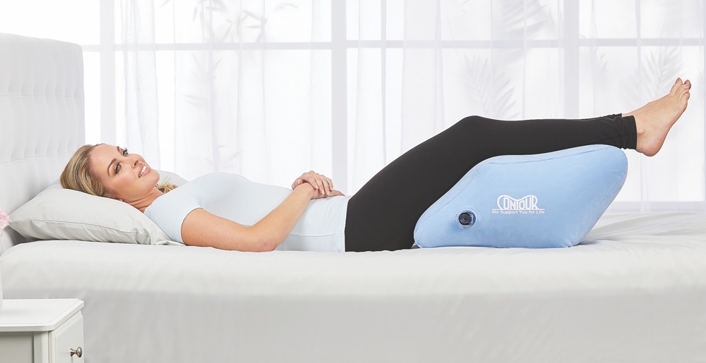 Woman on sofa using contour leg pillow at 40° angle to relieve pressure